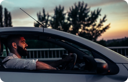 Man drives vehicle with a sunset in the background.